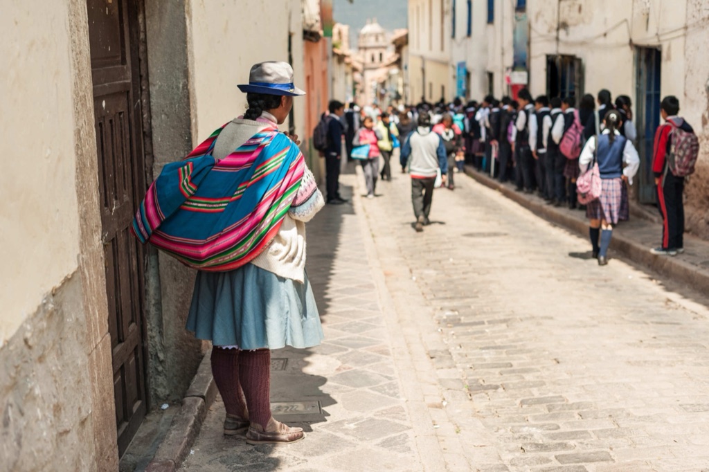 An Inca stone wall in Cusco with a street running beside it.