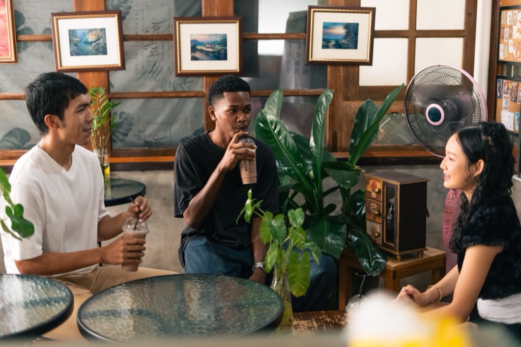 Three people talking around a table, one of them clearly hosting the others.